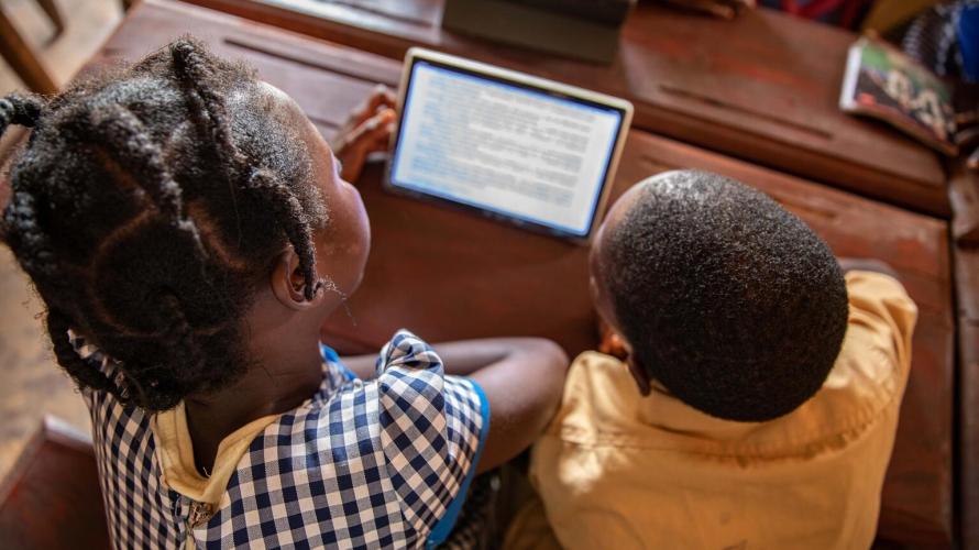 girl and boy student reading from a tablet