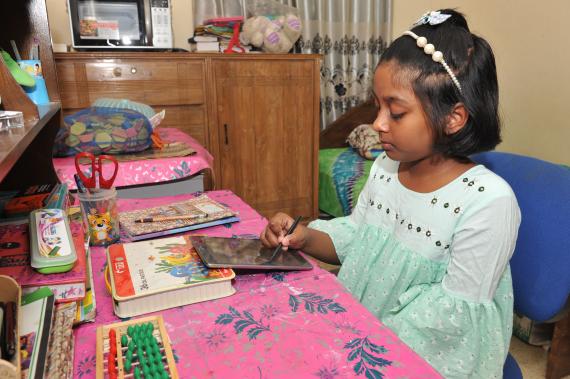 A girl uses her computer tablet to complete schoolwork